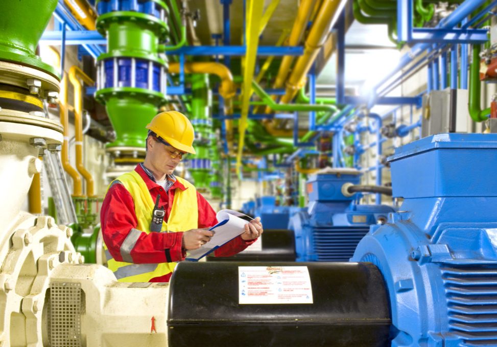 Engineer looking aty a checklist during maintenance work in a large industrial engine room